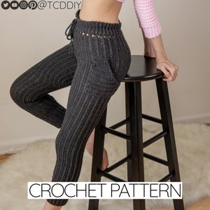 May include: Crochet pattern for a pair of gray crochet pants with a drawstring waist and a pocket on the back. The pants are shown on a model sitting on a black stool.