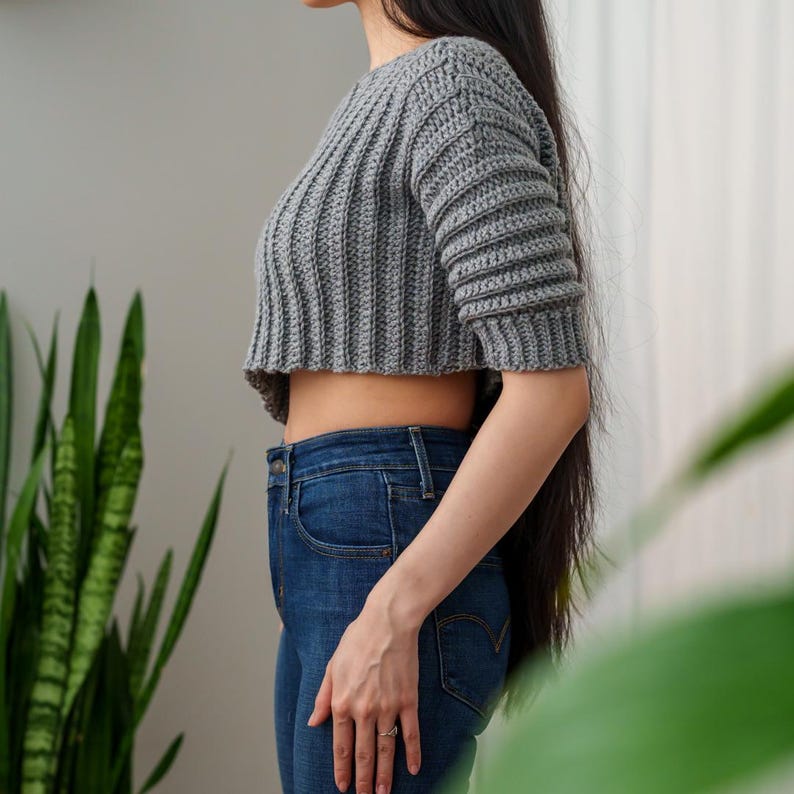 TCDDIY crochet pattern for an Off-the-Shoulder Cropped Sweater with short sleeves, ribbing, and open hem design, crafted with Lion Brand Pound of Love in Oxford Grey, side view.