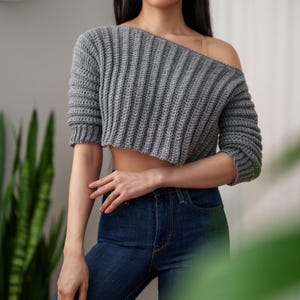 TCDDIY crochet pattern for an Off-the-Shoulder Cropped Sweater featuring short sleeves, ribbing, and open hem design, crafted with Lion Brand Pound of Love in Oxford Grey.