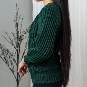 TCDDIY crochet pattern for a classic cropped crewneck sweater featuring cable and alpine stitches with ribbing details, made using Big Twist Soft yarn in Hunter Green, side view.