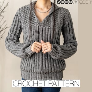 Può includere: Un maglione di uncinetto grigio con scollo a V e maniche lunghe. Il maglione ha un motivo a punto testurizzato e un orlo a coste. CROCHET PATTERN è scritto in testo nero nella parte inferiore dell'immagine.
