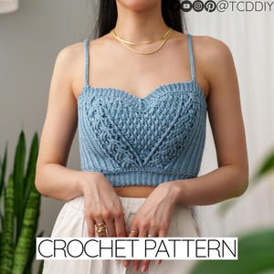 May include: A blue crochet crop top with a heart-shaped design. The top has thin straps and a close-fitting style.  CROCHET PATTERN is written in black text at the bottom of the image.