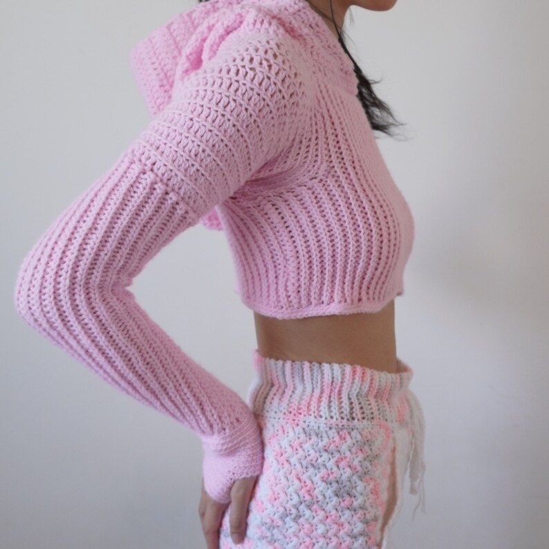 TCDDIY crochet pattern for a Long Sleeve Cropped Hoodie with thumbhole cuffs, ribbed sleeves, crafted using Lion Brand Pound of Love yarn in Pastel Pink, side view.