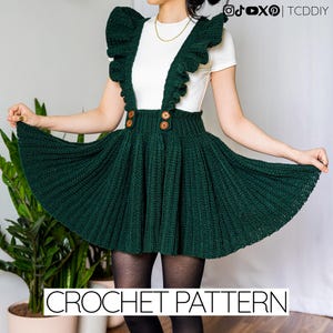 Könnte beinhalten: Dunkelgrüner Häkelrock mit Trägern und großen Holzknöpfen. Der Rock hat ein plissiertes Design und wird mit einem weißen Oberteil kombiniert. Der Text "CROCHET PATTERN" wird am unteren Bildrand angezeigt.