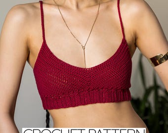 May include: A deep red crochet crop top featuring thin spaghetti straps, a scoop neckline, and a ribbed hem band. The garment displays a textured stitch pattern throughout the bodice. The text CROCHET PATTERN is visible at the bottom.