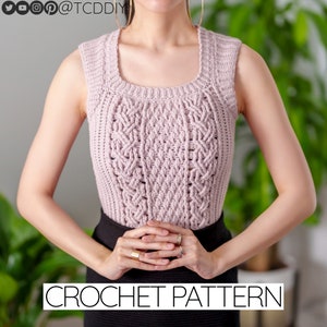 Pode incluir: Um close-up de um top rosa de crochê sem mangas com um padrão de tricô trançado. O texto "CROCHET PATTERN" está na parte inferior da imagem.