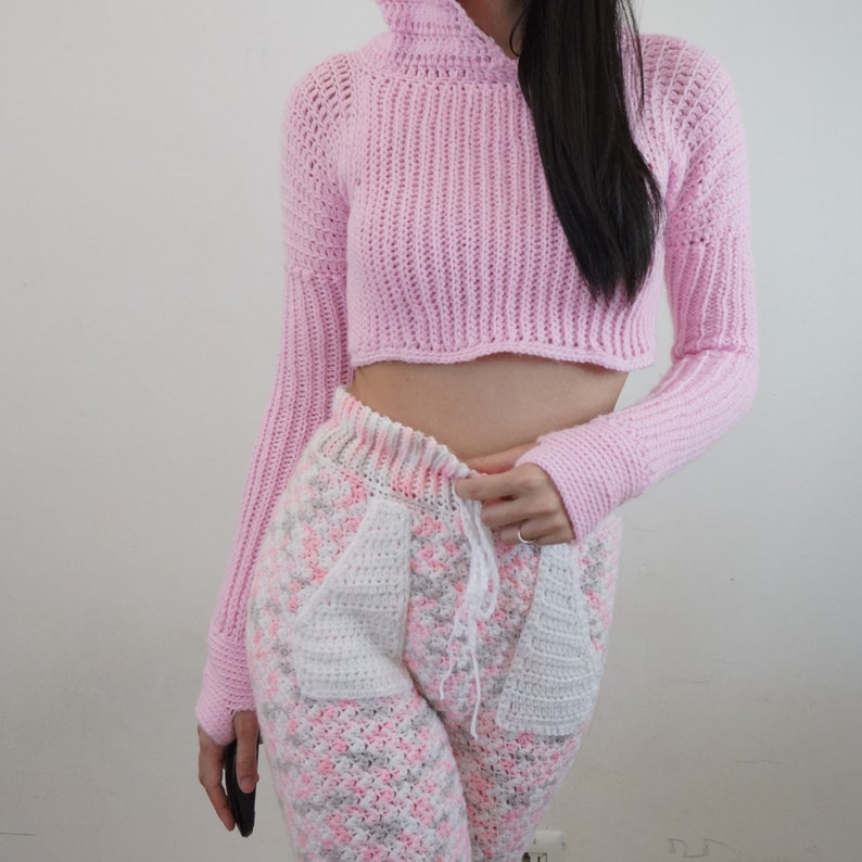 TCDDIY crochet pattern for a Long Sleeve Cropped Hoodie with thumbhole cuffs, ribbed sleeves, and customizable sizing, crafted using Lion Brand Pound of Love yarn in Pastel Pink.