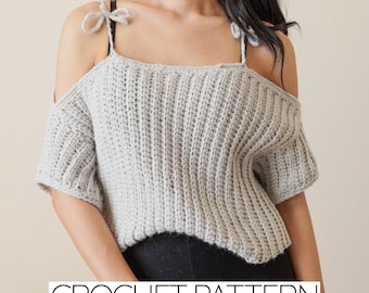 May include: A crochet pattern for a gray off-the-shoulder top with short sleeves and a tie detail at the shoulders. CROCHET PATTERN is written in white text at the bottom of the image.