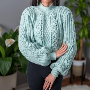 TCDDIY crochet pattern for a cropped cable stitch sweater with a mock neck and alpine stitch detailing, crafted using Caron One Pound yarn in Pale Green.