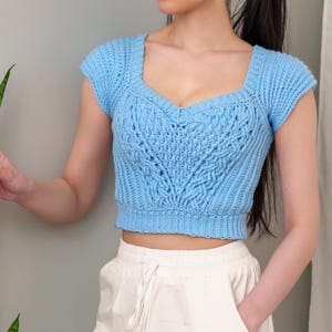 TCDDIY crochet pattern for a sweetheart cable stitch cropped T-shirt top with alpine stitch and ribbed detailing, crafted using Caron One Pound yarn in Pastel Blue.