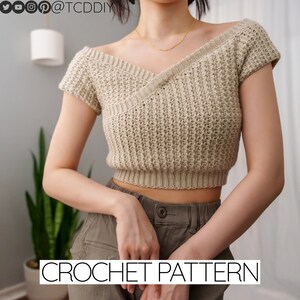 以下が含まれることがあります： Vネックと短い袖のベージュのクロシェトップ。トップはフロントにクロスデザインがあり、ウエストがクロップされています。CROCHET PATTERNは画像の下部に黒文字で書かれています。