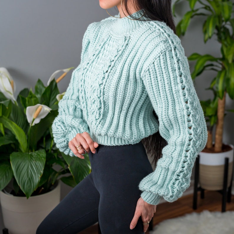 TCDDIY crochet pattern for a cropped cable stitch sweater with a mock neck and alpine stitch detailing, crafted using Caron One Pound yarn in Pale Green, side view.