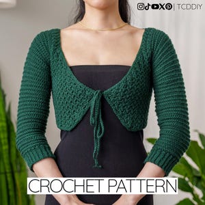 May include: A dark green crochet shrug with long sleeves and a tie closure. The shrug is made of a textured yarn and has a square neckline. The text "CROCHET PATTERN" is displayed at the bottom of the image. The image also includes social media icons.