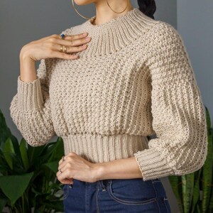 TCDDIY crochet pattern for a modern wide-collar Trinity stitch 3/4 sleeve sweater with a customizable fit, crafted using Baby Bernat Sport yarn in Baby Taupe.