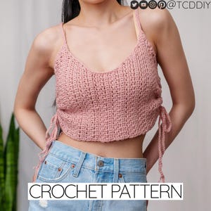 May include: A pink crochet crop top with adjustable straps and a tie detail at the sides. CROCHET PATTERN is written in white text at the bottom of the image.