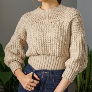 TCDDIY crochet pattern for a modern wide-collar Trinity stitch 3/4 sleeve sweater with a customizable fit, crafted using Baby Bernat Sport yarn in Baby Taupe.