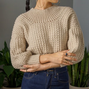 TCDDIY crochet pattern for a modern wide-collar Trinity stitch 3/4 sleeve sweater with a customizable fit, crafted using Baby Bernat Sport yarn in Baby Taupe.