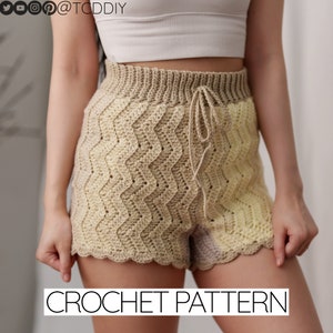 May include: Crochet shorts pattern with a beige and yellow chevron design. The shorts have a drawstring waist and a scalloped hem.