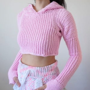TCDDIY crochet pattern for a Long Sleeve Cropped Hoodie with thumbhole cuffs, ribbed sleeves, and customizable sizing, crafted using Lion Brand Pound of Love yarn in Pastel Pink.
