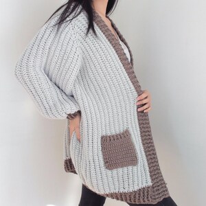 TCDDIY crochet pattern for an Oversized Reversible Cardigan featuring ribbing and pockets, crafted using Lion Brand Pound of Love yarn in Elephant Grey and Taupe, side view.