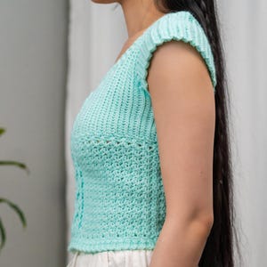 TCDDIY crochet pattern for a short sleeve cable stitch top with ribbing, featuring a Suzette stitch texture, made using Lion Brand Pound of Love yarn in Pastel Green, side view.