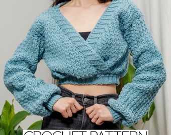 May include: A light blue crochet wrap sweater with long sleeves and a V-neck. The sweater is cropped and has a textured stitch pattern. CROCHET PATTERN is written in black text at the bottom of the image.