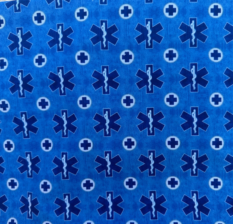 K&ouml;nnte beinhalten: Blauer Stoff mit einem sich wiederholenden Muster aus wei&szlig;en Kreisen, die ein Pluszeichen und blaue medizinische Lebensstern-Symbole enthalten.