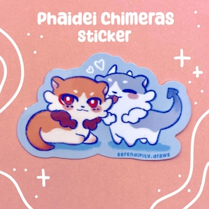 May include: A sticker featuring two cartoon chimeras. One is orange and white with red eyes, the other is blue and white. The sticker has the text "Phaidei Chimeras Sticker" at the top and "serendipity.draws" at the bottom.