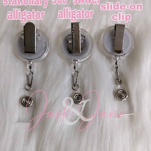 May include: Three clear plastic retractable badge holders with different types of clips. The first holder has a stationary alligator clip, the second has a 360 degree swivel alligator clip, and the third has a slide-on clip.
