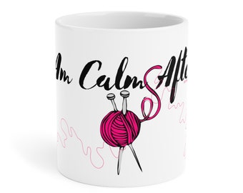 Op de afbeelding: Witte keramische mok met zwarte tekst die "I'm Calm After..." luidt en een roze bol garen met breinaalden.