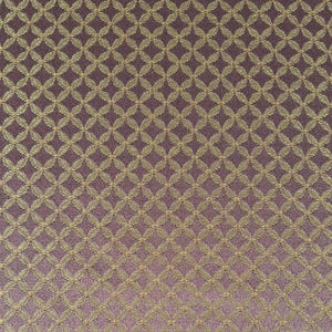 Puede incluir: Primer plano de una tela con un patrón repetido de formas florales doradas estilizadas sobre un fondo morado oscuro. El patrón crea un diseño geométrico texturizado en la superficie de la tela.