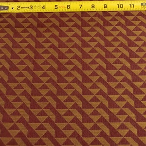 May include: A fabric with a geometric pattern of brown triangles on a red background.