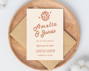 May include: A cream-colored wedding invitation with a red disco ball graphic. The text reads "Amelia & Jonas are getting married September 21, 2023 3 o'clock in the afternoon Juniper Hotel, Boston, MA Celebration to follow."