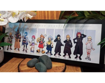 May include: A framed print of Kingdom Hearts characters. The artwork displays a group of stylized figures in various outfits, set against a light blue and white background. The black frame surrounds the print, which is displayed on a wooden surface. The print has the words "Kingdom Hearts".