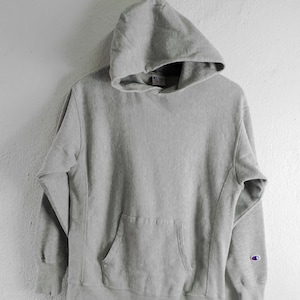May include: A grey Champion hoodie with a kangaroo pocket and a small Champion logo on the left sleeve.