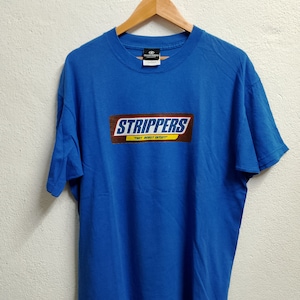 Könnte beinhalten: Ein königsblaues T-Shirt mit einem Aufdruck einer Schokoladentafel, auf der "Strippers" und "They Really Get Off" in weiß steht.