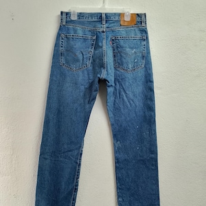 Puede incluir: Un par de pantalones vaqueros azules de mezclilla con un parche de cuero en la parte posterior de la cintura.