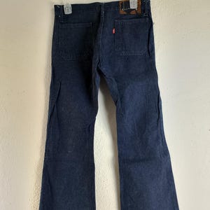 May include: A pair of dark blue denim bell bottom jeans with a brown leather patch on the back waistband.