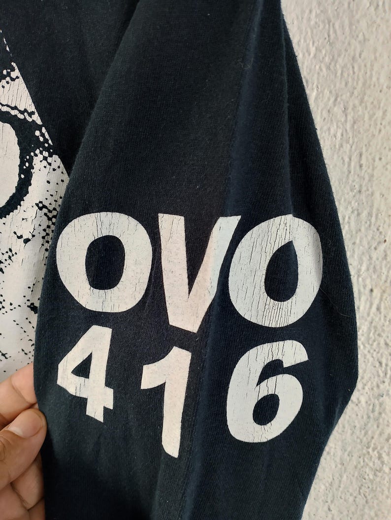 Pode incluir: Manga de camisa preta com texto branco. O texto "OVO 416" est&aacute; escrito em negrito, com um efeito desgastado. O tecido parece macio e o desenho &eacute; impresso na manga.