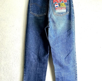 May include: Blue denim jeans with a Pepsi patch on the back pocket. The patch features the Pepsi logo and the text "Come Alive!" in red and white. The text "America's Favorite" is also on the patch.