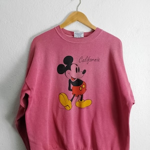Puede incluir: Una sudadera rosa con un gráfico vintage de Mickey Mouse y el texto "California".