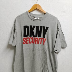 May include: Grey t-shirt with black "DKNY SECURITY" text printed on the front.