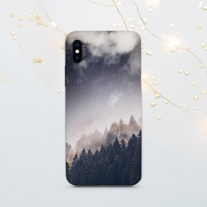 Könnte beinhalten: Eine Smartphone-Hülle mit einer Waldlandschaft, Sternenhimmel und Wolken. Das Design zeigt einen nebligen Wald mit dunkelgrünen Bäumen und einen Farbverlauf von Dunkelblau bis Weiß.