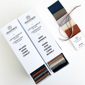 Op de afbeelding: Twee witte dozen met lederen monsters voor verschillende meubelsets. De dozen zijn gelabeld met de namen van de sets, zoals Milano, Soho, Como, Chalet, Kent, Monaco, Roma, Riva, Firenze, Capri en Beverly. De dozen zijn open en de lederen monsters zijn zichtbaar.