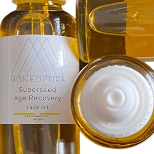 Puede incluir: Primer plano de una botella de vidrio transparente de Moneopura Supersed Age Recovery Face Oil. La botella tiene una etiqueta blanca con el nombre de la marca y los detalles del producto. El aceite es de color dorado y la tapa es blanca.