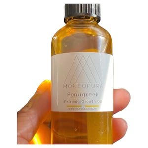 May include: A clear glass bottle filled with amber-colored liquid, labeled "Moneopura Fenugreek Extreme Growth Oil." The label features a geometric design and the website address. The bottle is held against a white background.