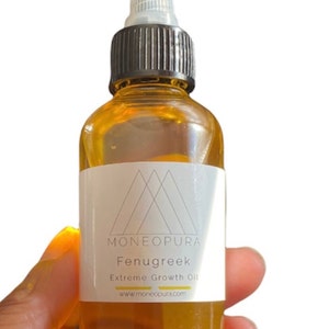 May include: A clear glass bottle filled with amber-colored oil. The bottle has a black cap and a white label with the text "MONEOPURA Fenugreek Extreme Growth Oil" and a website address. The bottle is held by a hand.