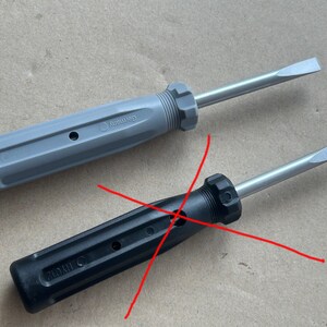 May include: Two screwdrivers, one gray and one black, with a red X drawn over them. The gray screwdriver has the word "Germany" printed on the handle. The black screwdriver has the word "China" printed on the handle.