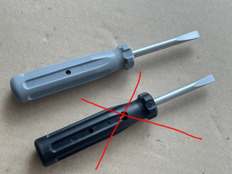 May include: Two screwdrivers, one gray and one black, with a red X drawn over them. The gray screwdriver has the word "Germany" printed on the handle. The black screwdriver has the word "China" printed on the handle.