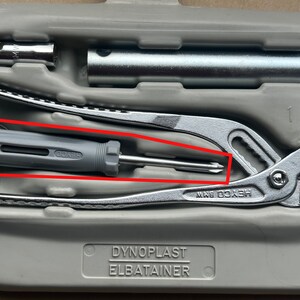 May include: A gray and silver multi-tool set in a gray plastic case. The set includes a pair of pliers, a screwdriver, and a wrench. The case has the text "Dynoplast Elbatainer" printed on it.